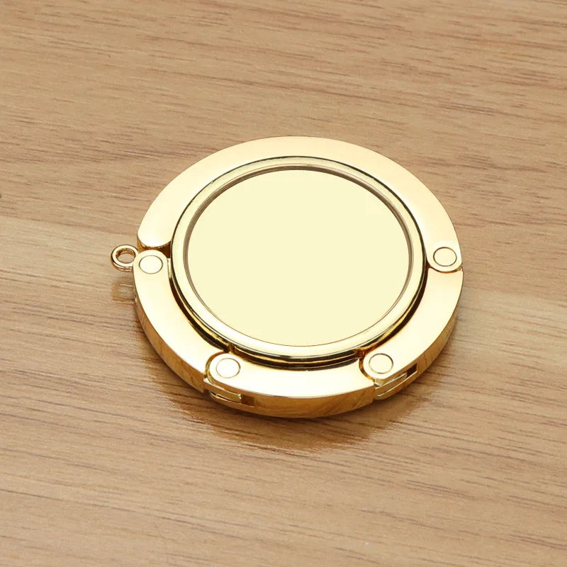 A round, gold-colored metal object with a central opening and four small loops for hanging.