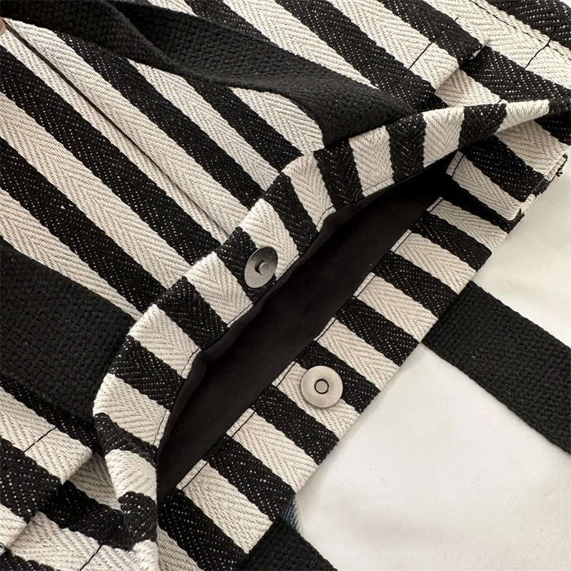 Gros plan d'un sac bandoulière en toile rayée noire et blanc cassé tendance.