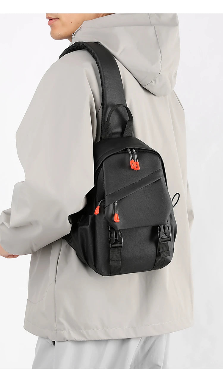 Un homme portant une veste gris clair tient un sac de sport noir pour l'extérieur.