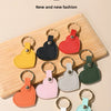 A collection of colorful leather heart keychains displayed on a wooden board.