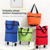 A collection of foldable shopping bags in blue, green, and red hanging on a white surface.