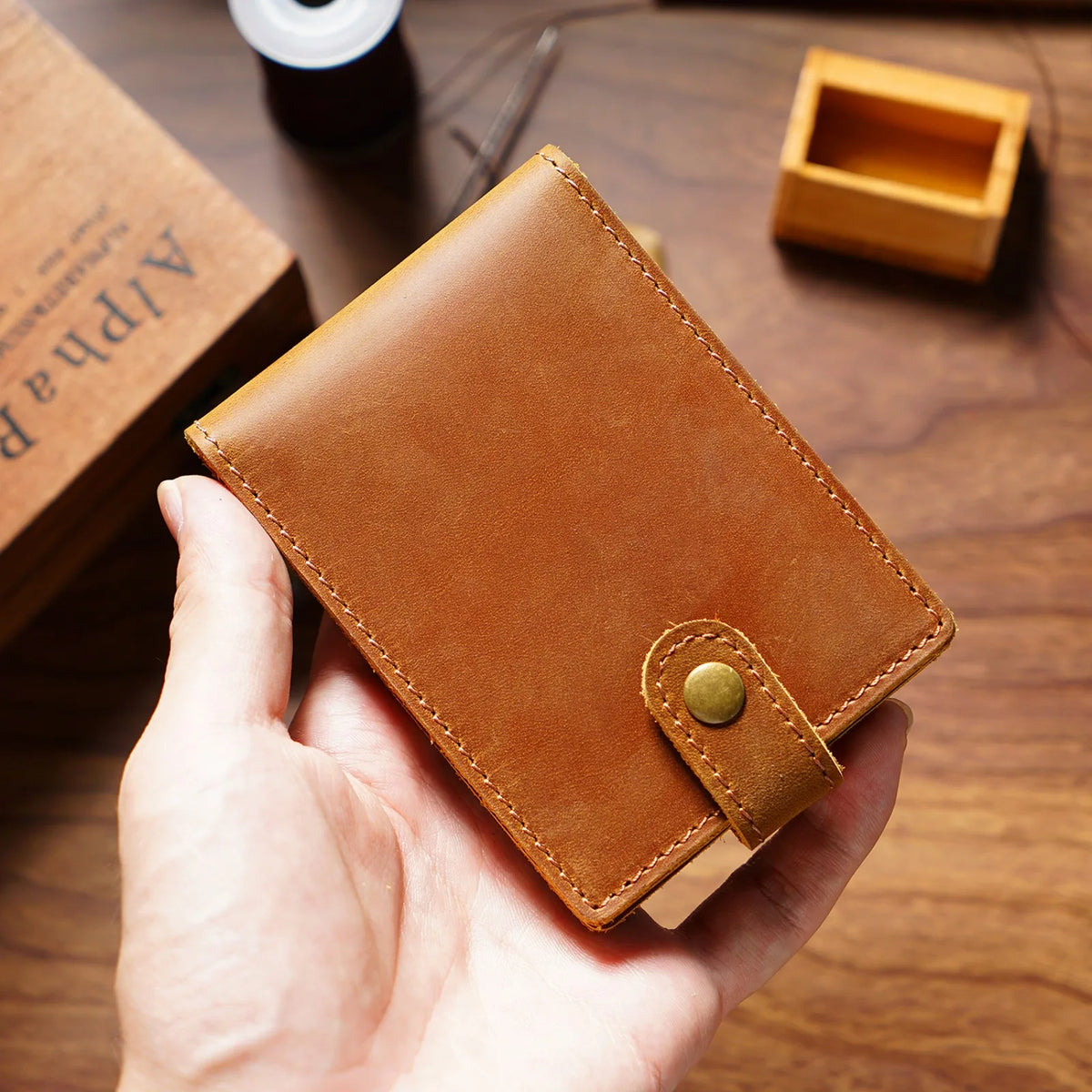 Une main tient un portefeuille pliable en cuir brun pour les papiers d'identité et cartes sur une surface en bois.