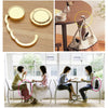 A gold-toned folding alloy handbag hanger hook is shown with a curved shape and a circular design, alongside a women's handba