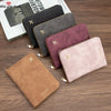 A collection of slim passport wallets in various colors including black, gray, and mauve, displayed on a wooden surface.