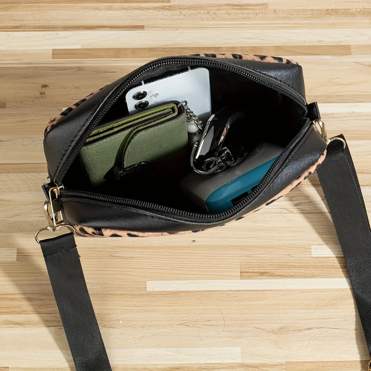 A black leopard print crossbody bag with a flap open, showing a white card and a dark wallet inside.