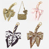 A collection of four bow bag chain strap extensions in various colors and patterns for handbags.