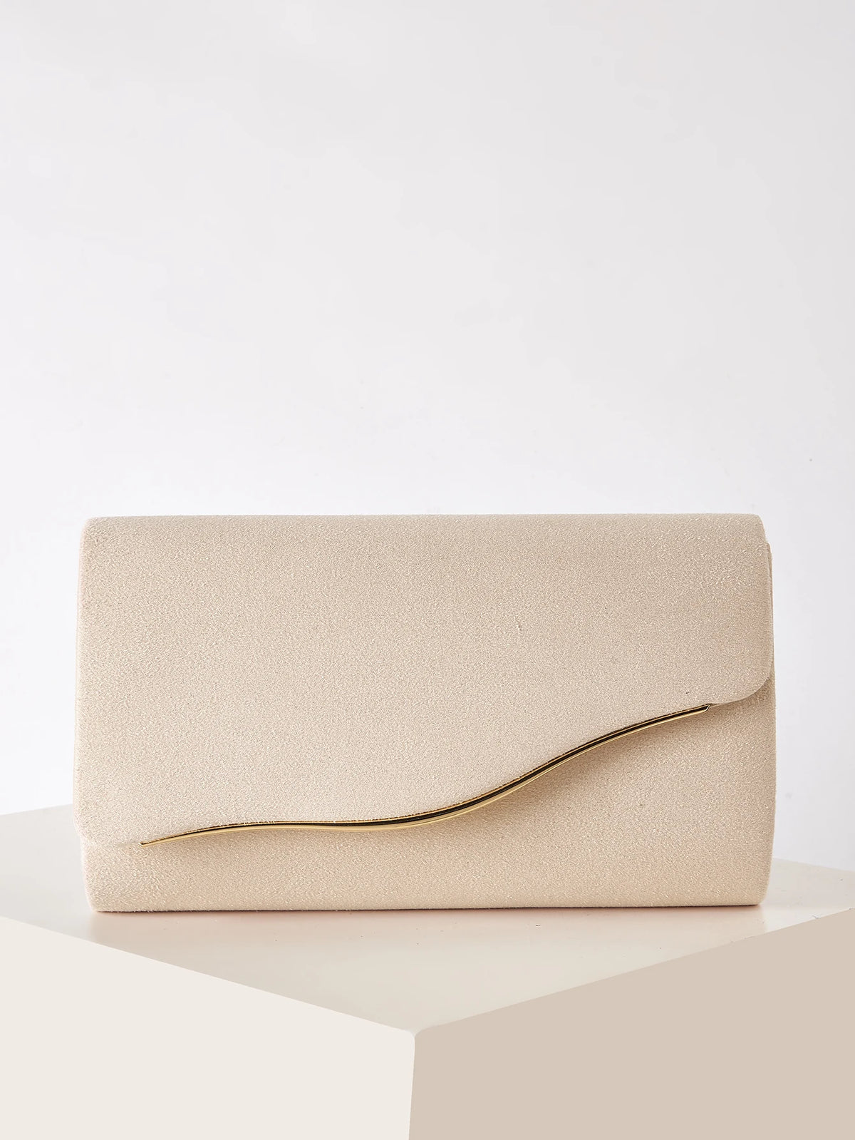 A beige velvet evening clutch with a gold-toned detachable shoulder strap resting on a white surface.