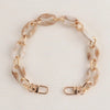 A delicate gold-toned chain strap made of marbled beige and white acrylic is displayed against a white background.