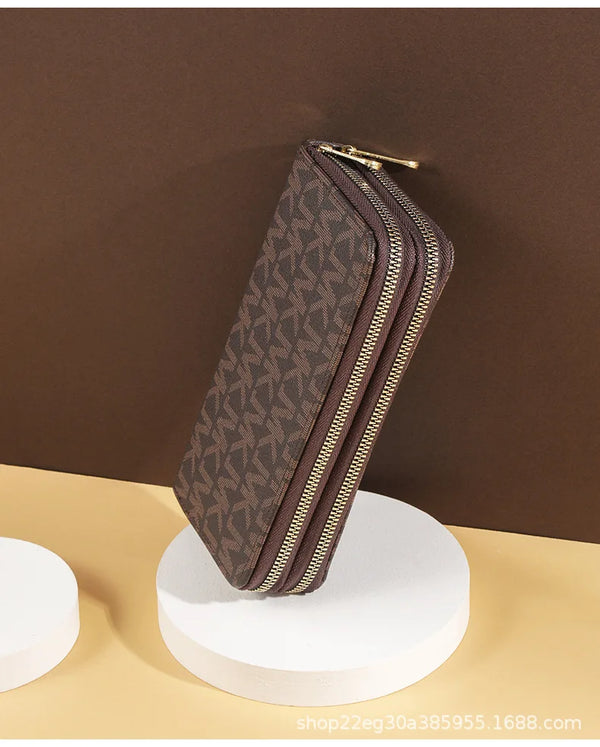 A brown patterned PU leather zippered wallet is displayed on a white circular stand against a dark background.