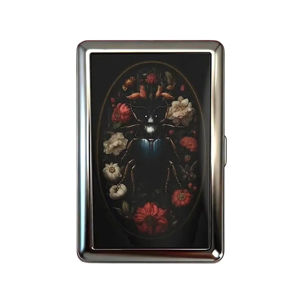 A vintage metal card holder with a dark background featuring an intricate floral design.
