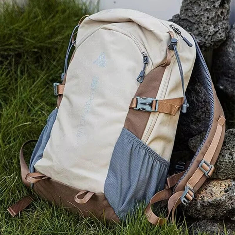 A beige and brown durable 80L waterproof hiking backpack resting on a dark rock amidst green grass.