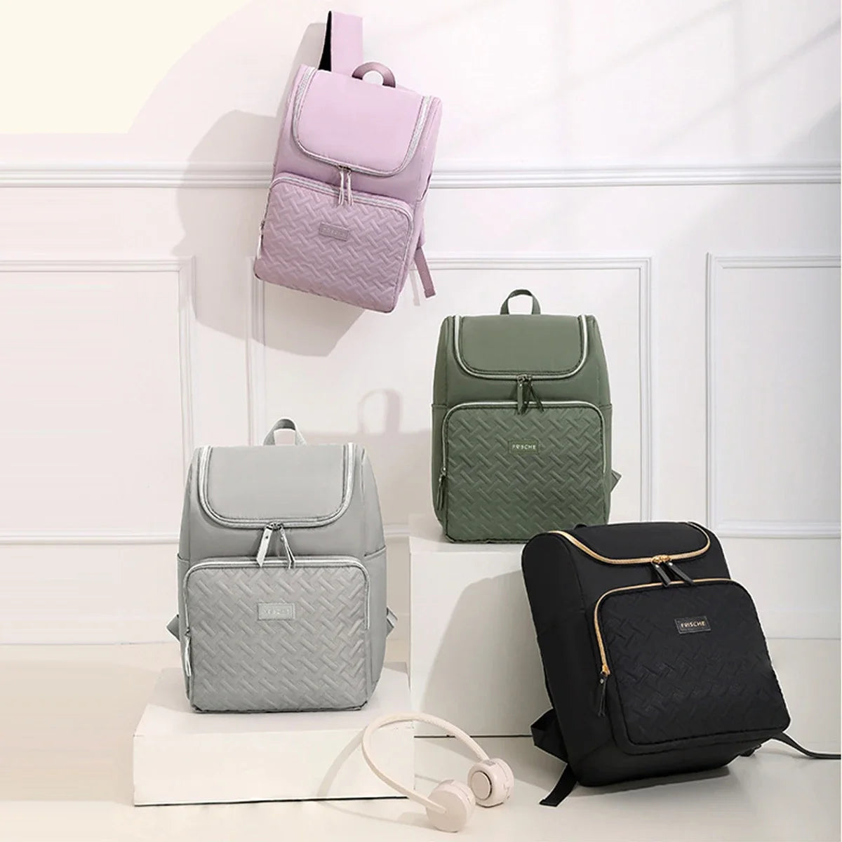 A collection of three insulated travel backpacks in lilac, olive green, and black resting on a white surface.