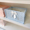 Light blue quilted cotton storage basket with a white bow on a white shelf