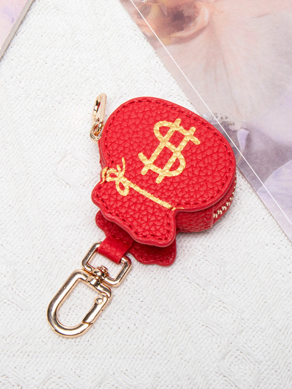 Bolsa de monedas con forma de corazón roja y signo de dólar dorado en llavero de plata.
