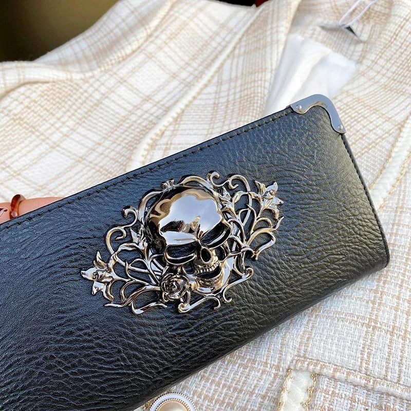 A black leather wallet with an ornate silver skull design resting on a light-colored fabric.