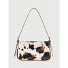 A beige and black cow print single shoulder bag with a brown adjustable strap.
