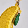A yellow fruit-shaped PU leather coin purse keychain with a gold-toned clasp and a green fabric tag.