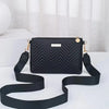 Black quilted leather crossbody bag with gold hardware and black strap displayed on a white surface.