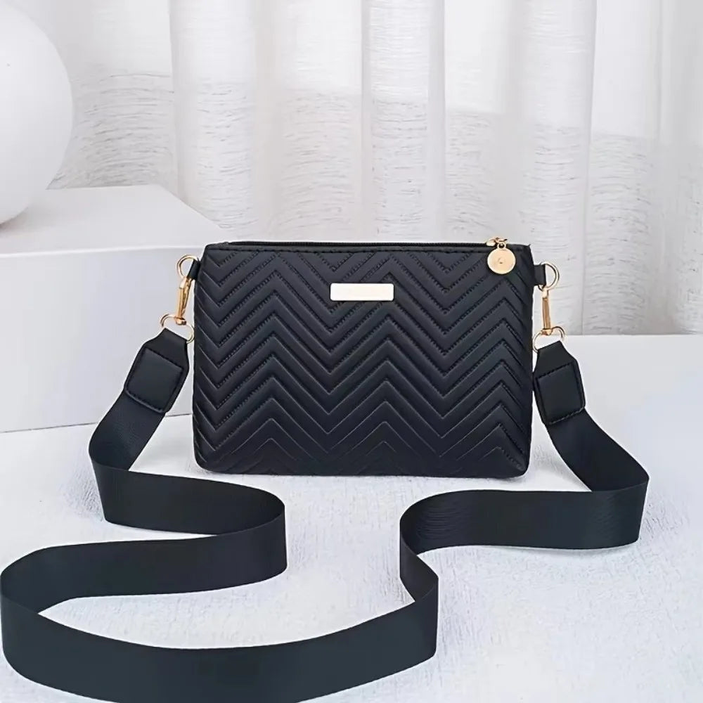 Black quilted leather crossbody bag with gold hardware and black strap displayed on a white surface.