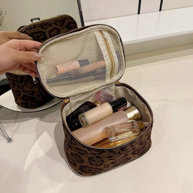 A brown faux suede cosmetic bag is open, revealing a netted interior and several makeup products.