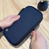 A dark blue waterproof RFID blocking passport holder is shown being held by a hand on a wooden surface.