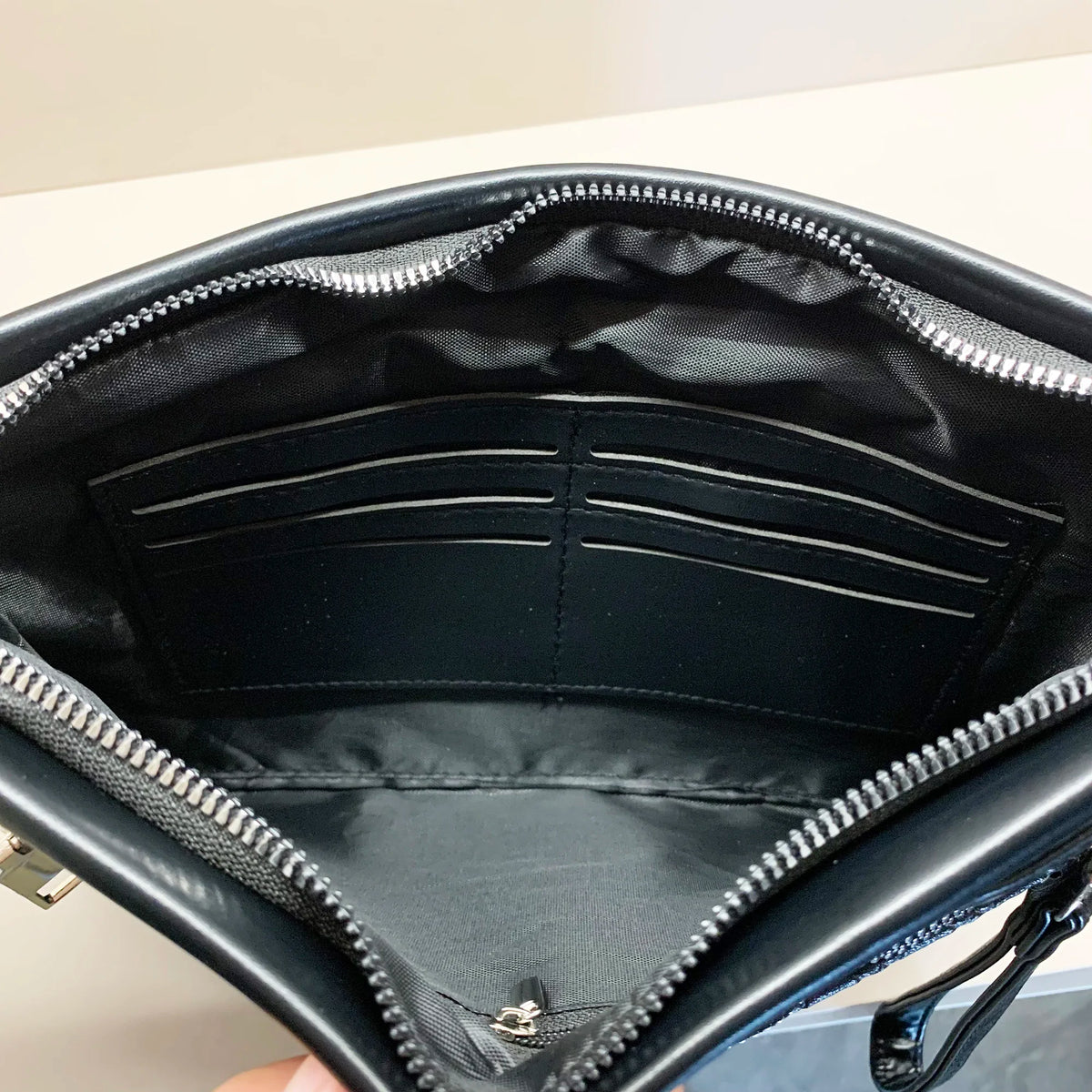 A black PU leather clutch bag is shown open, displaying its interior lining and zipper details.