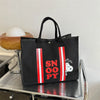 Black canvas shoulder bag featuring red and white stripes and a Snoopy cartoon design.