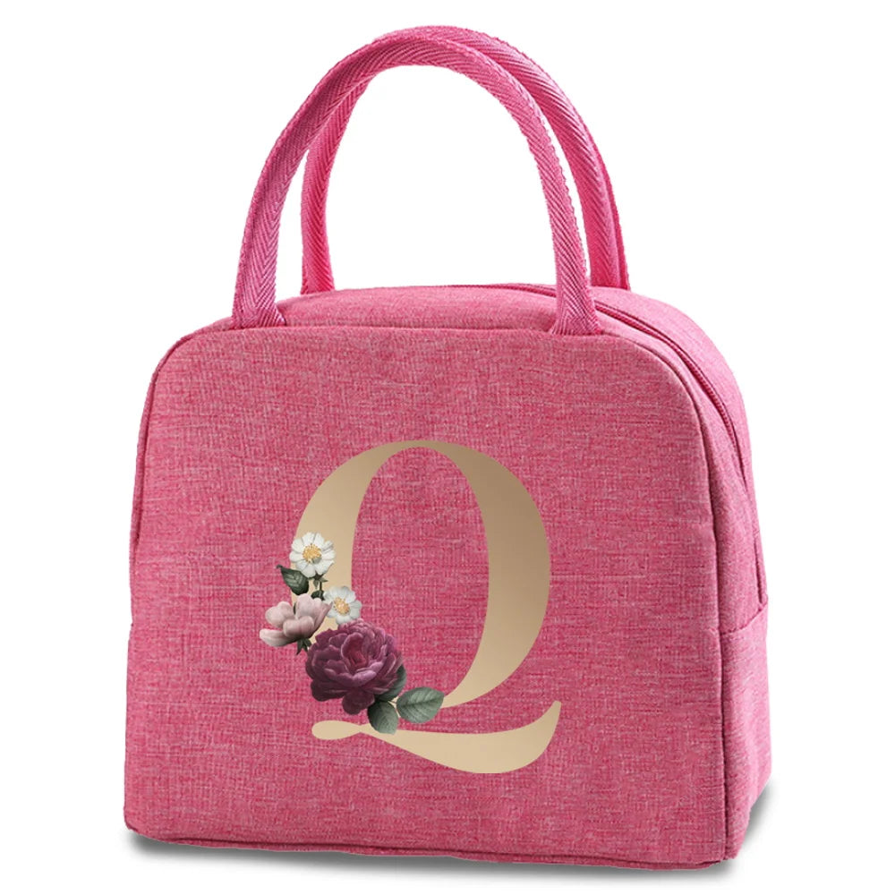 A pink insulated canvas lunch bag featuring a large gold letter Q design.
