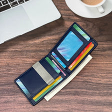Portefeuille noir bleu marine en fibre de carbone, posé sur une surface en bois à côté d'un ordinateur portable et d'une tass