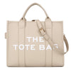 Sac cabas de luxe beige avec coutures verticales et quincaillerie dorée.