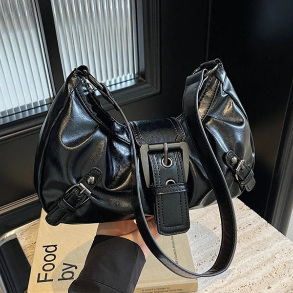 Black Y2K retro pleated shoulder bag resting on a wooden surface near a window.