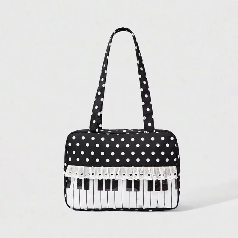 A black tote bag with white polka dots featuring a piano key trim and bow detail.