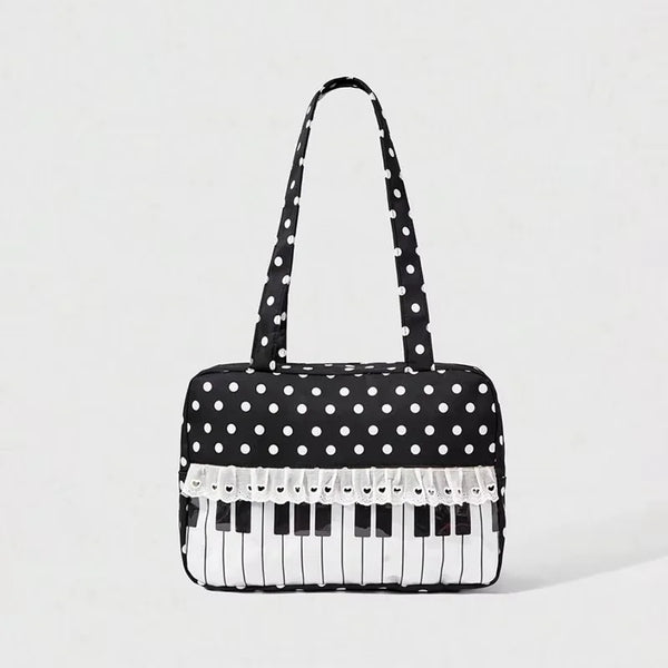 A black tote bag with white polka dots featuring a piano key trim and bow detail.
