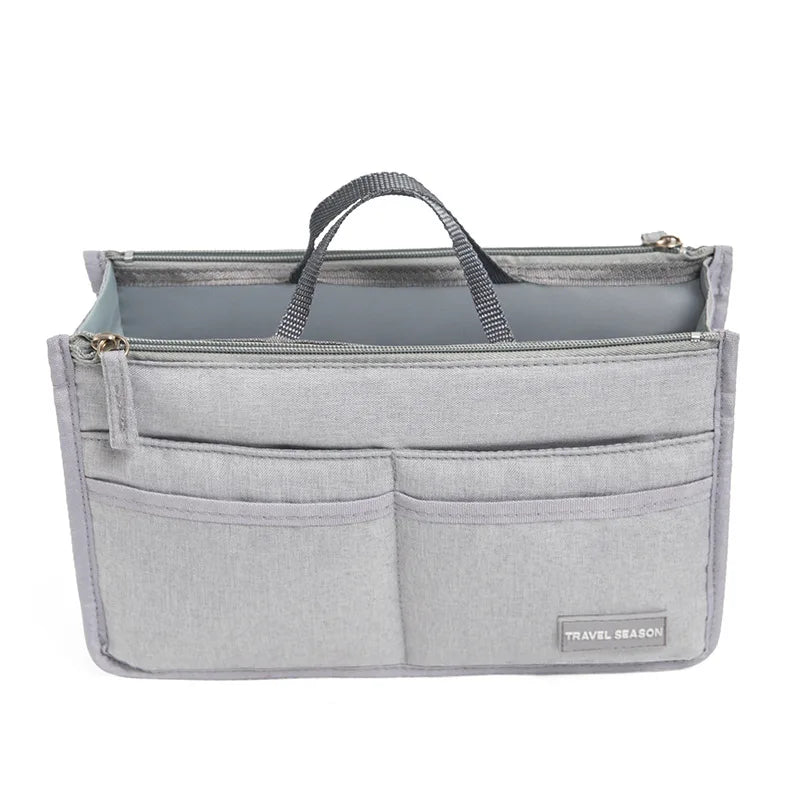 A gray fabric handbag organizer insert with a handle and multiple pockets.