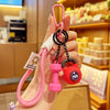 A hand holds a pink nylon D-shape fitness keychain with a black ring and a red charm.