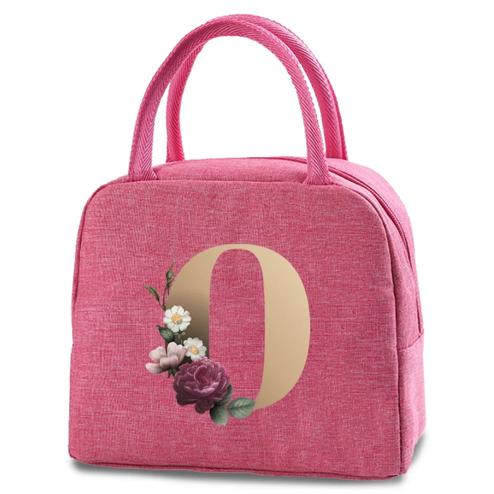 A pink insulated canvas lunch bag featuring a gold letter O design with small floral accents.