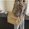 A person is holding a tan corduroy shoulder bag with a zipper on their shoulder while standing in a kitchen setting.