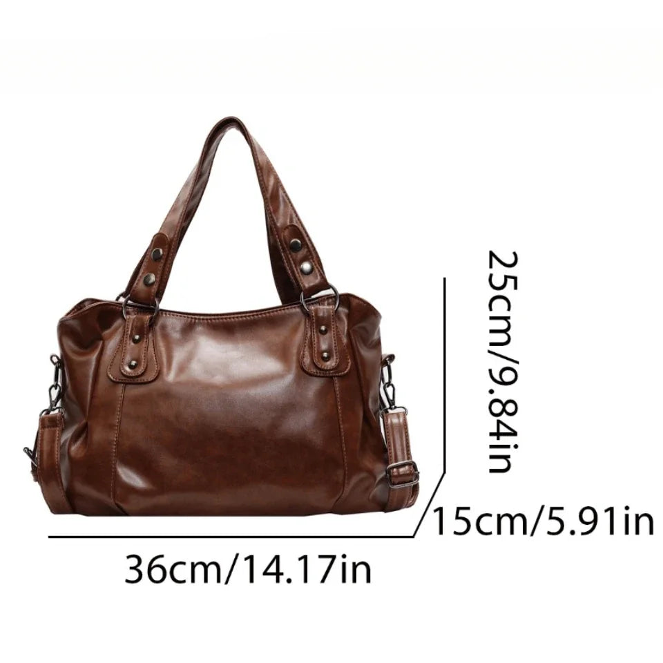 A brown vintage style leather tote bag with a crossbody strap shown from the front.