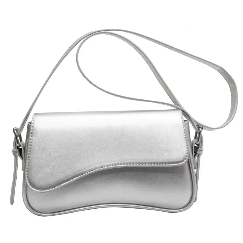 Bolso cruz de cuero vintage plateado con diseño curvo y suave.