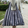 A black and white striped foldable oxford grocery tote bag carried by a person.