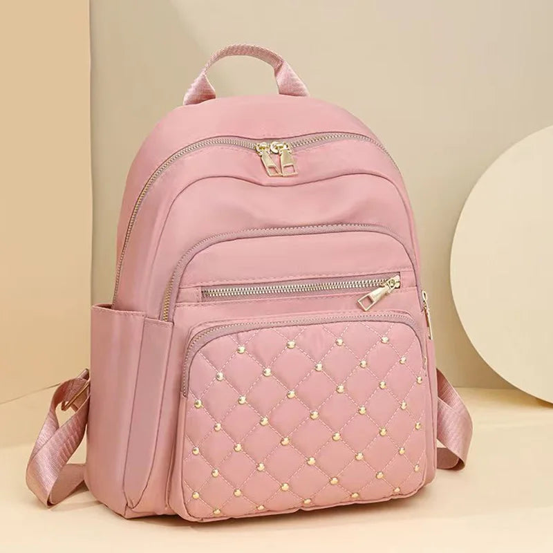 Pinkes gestepptes Kunstleder-Daypack mit Reißverschluss und Schulterriemen vor hellem Hintergrund.