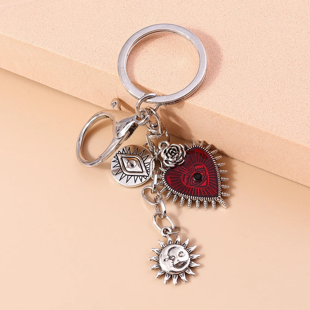 Silver gothic steampunk heart keychain featuring a red eye pendant and a sun charm