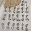 A collection of stainless steel alphabet letter charms with lobster clasps arranged on a white background.