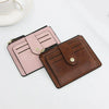 A pink and brown leather card holder wallet with a coin pocket resting on a white surface.