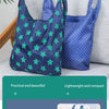 A dark blue reusable shopping bag with a green star pattern is shown next to a light gray surface.