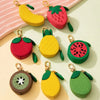 A collection of fruit-shaped PU leather coin purse keychains in red, yellow, and green.