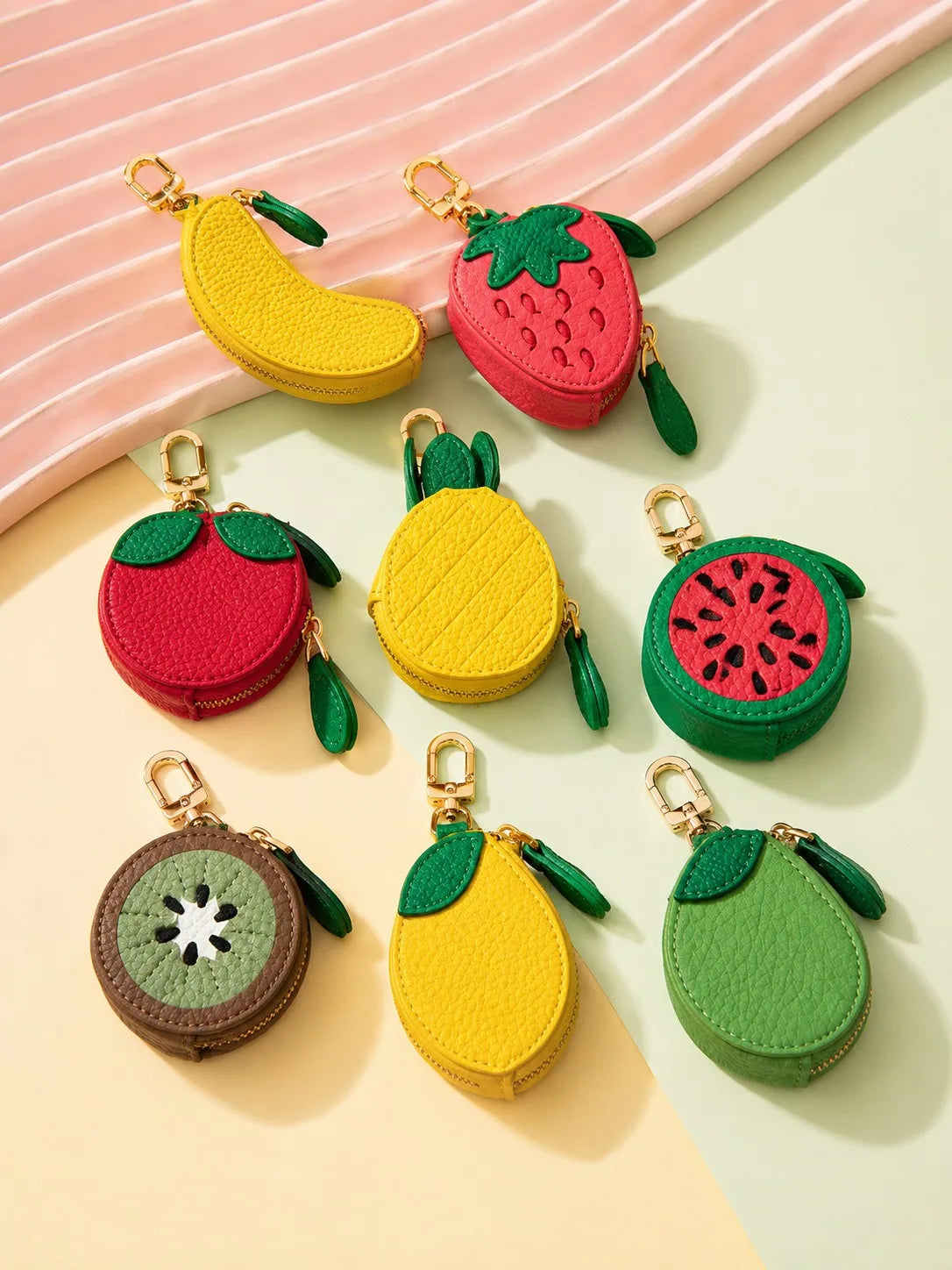 A collection of fruit-shaped PU leather coin purse keychains in red, yellow, and green.