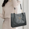 A woman holds a black and white geometric letter M tote bag with gold hardware against a light background.