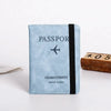 A light blue passport wallet with black trim featuring a stylized airplane icon and the text Charm Eternity travel wallet.