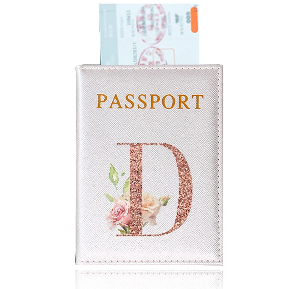 A pink leather passport holder with a gold embossed letter D and floral accents.